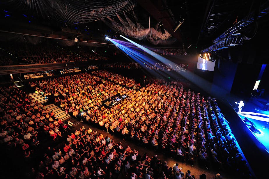 Audience members watch a concert on stage.