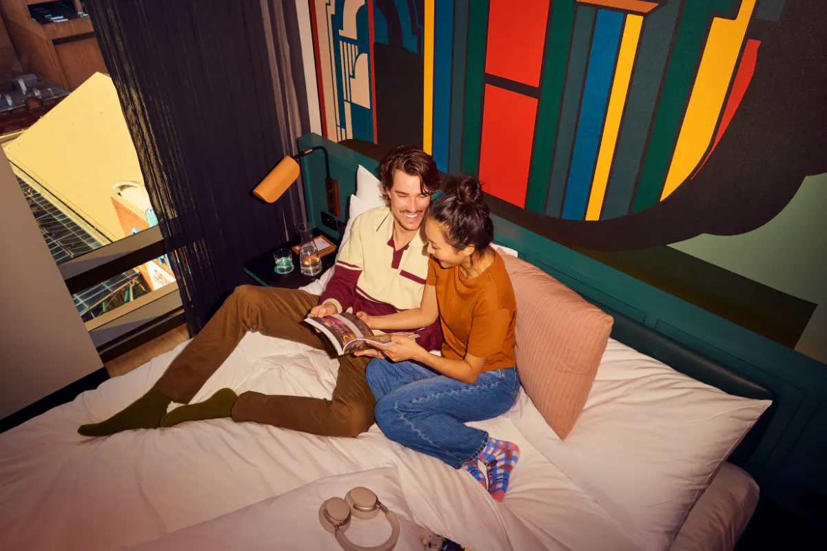 Couple in hotel bed reading brochure