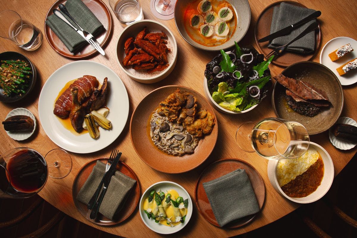 A full dinner table featuring assorted dishes, plates, and glasses of wine.