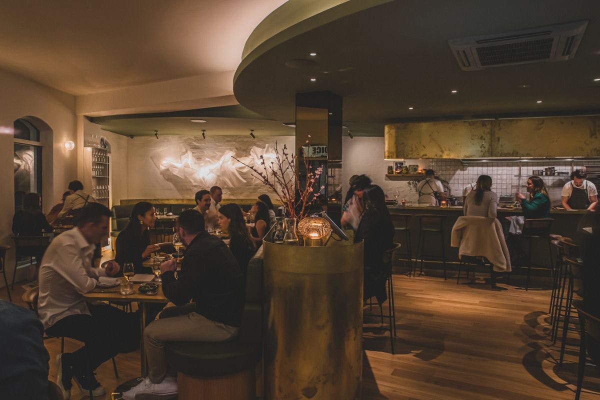 People sitting inside a wine bar enjoying food and drink.